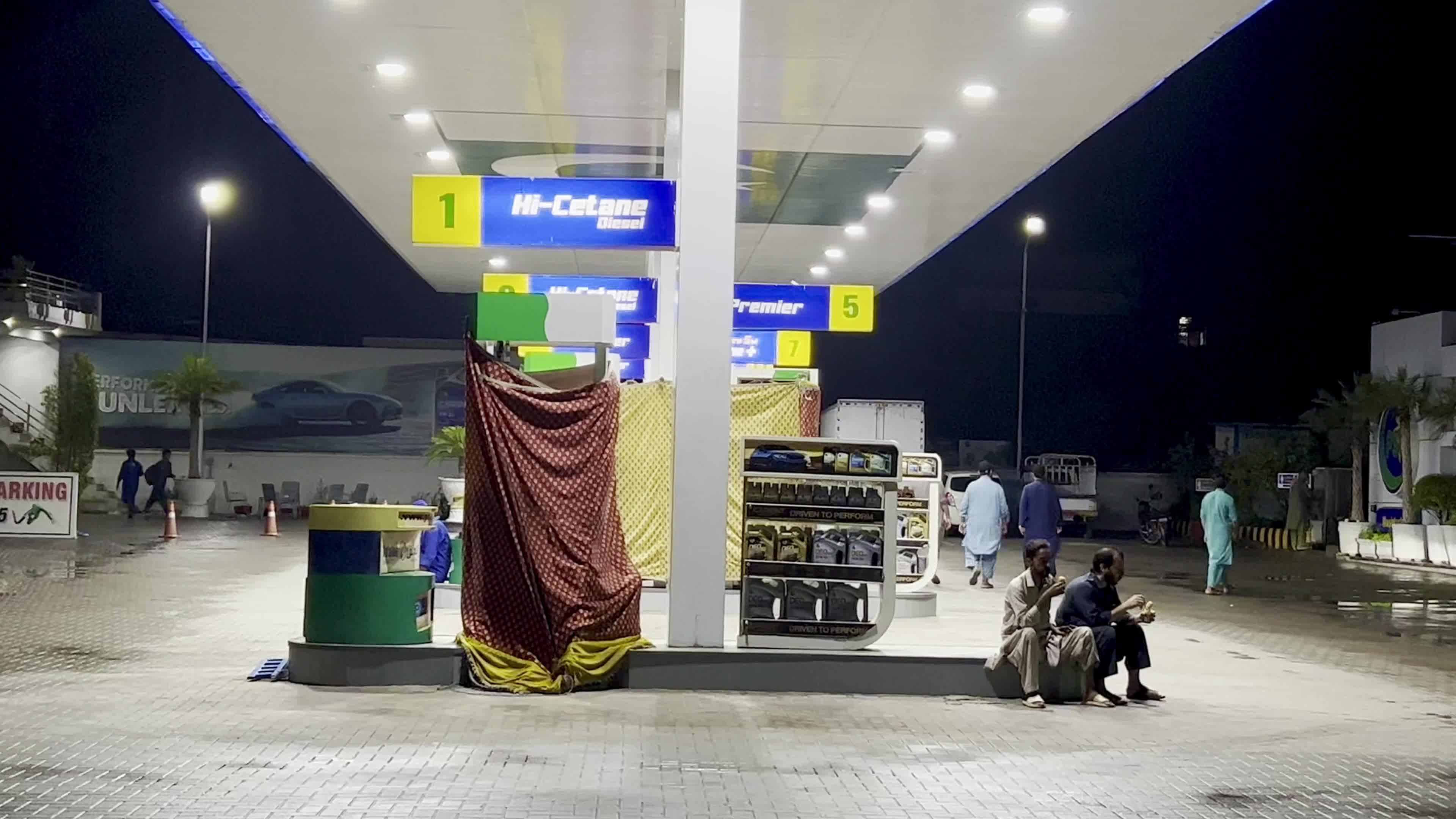 Petrol pump attendants stand beside covered fuel dispensers after fuel price hike in Peshawar