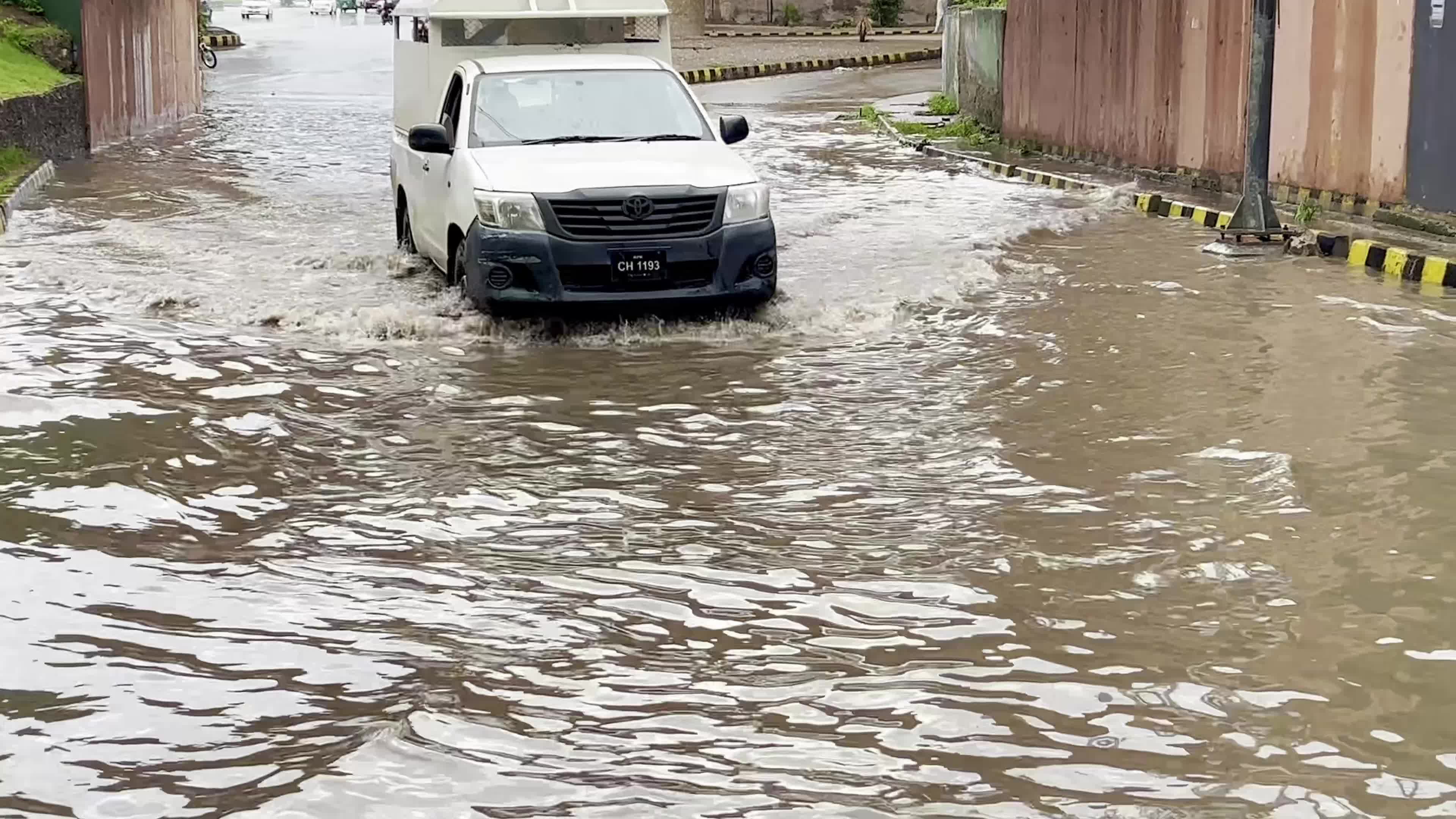 Vehicles drive along flooded road after heavy monsoon rainfall in Peshawar