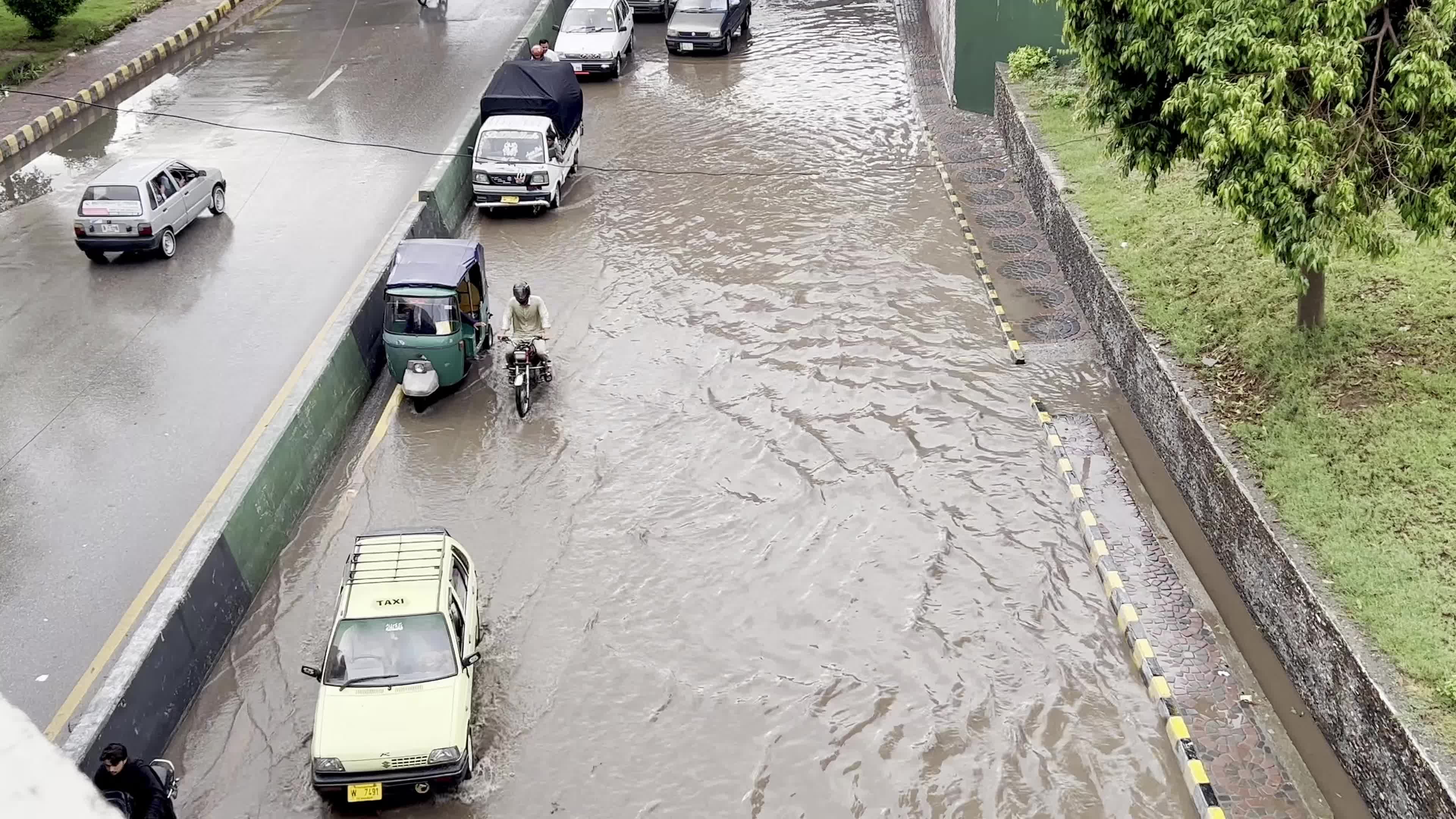 Vehicles drive along flooded road after heavy monsoon rainfall in Peshawar