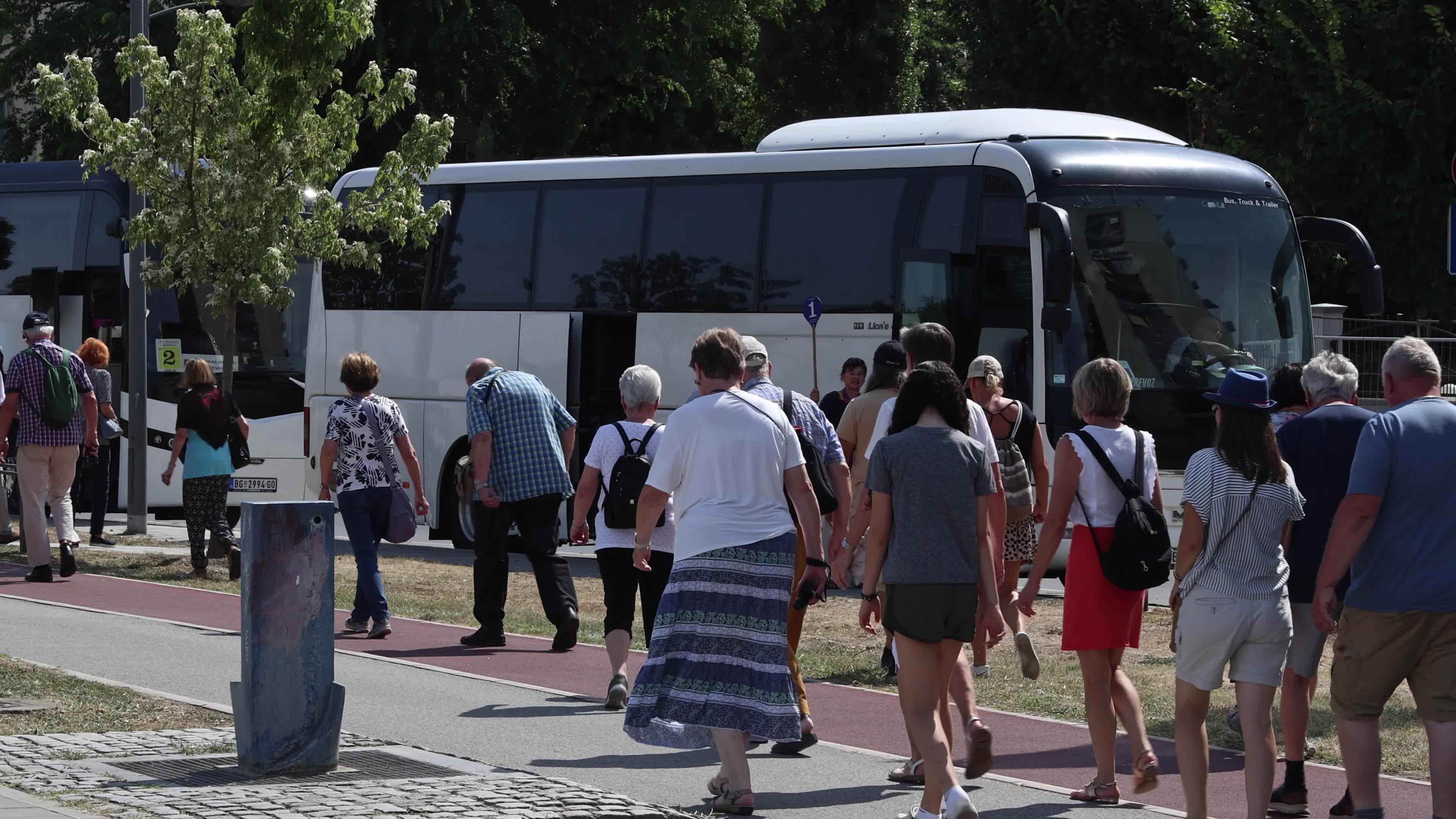 Tourists walk towards a tour bus
