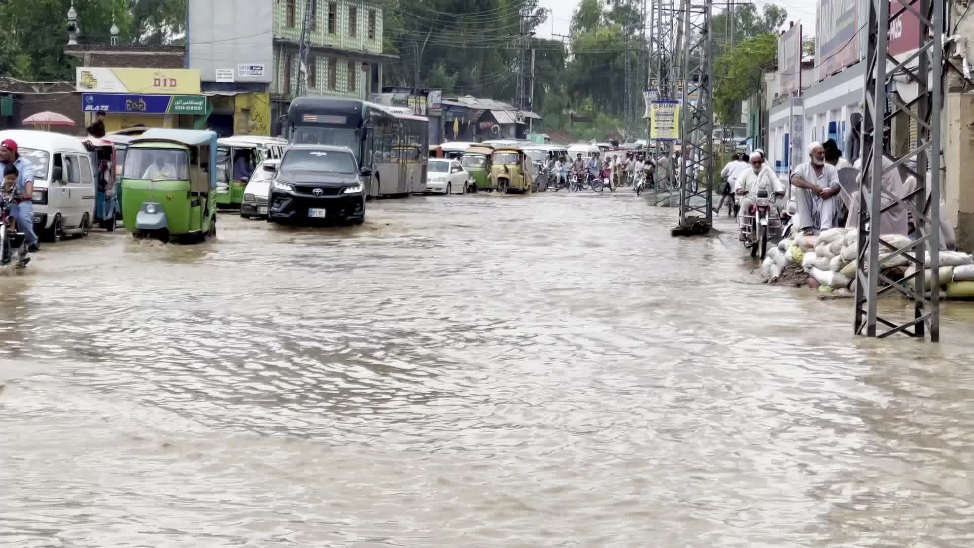 Residents wade through floodwaters after heavy monsoon rains in Peshawar