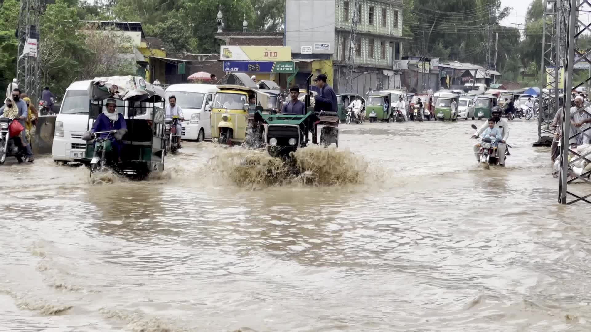 Residents wade through floodwaters after heavy monsoon rains in Peshawar