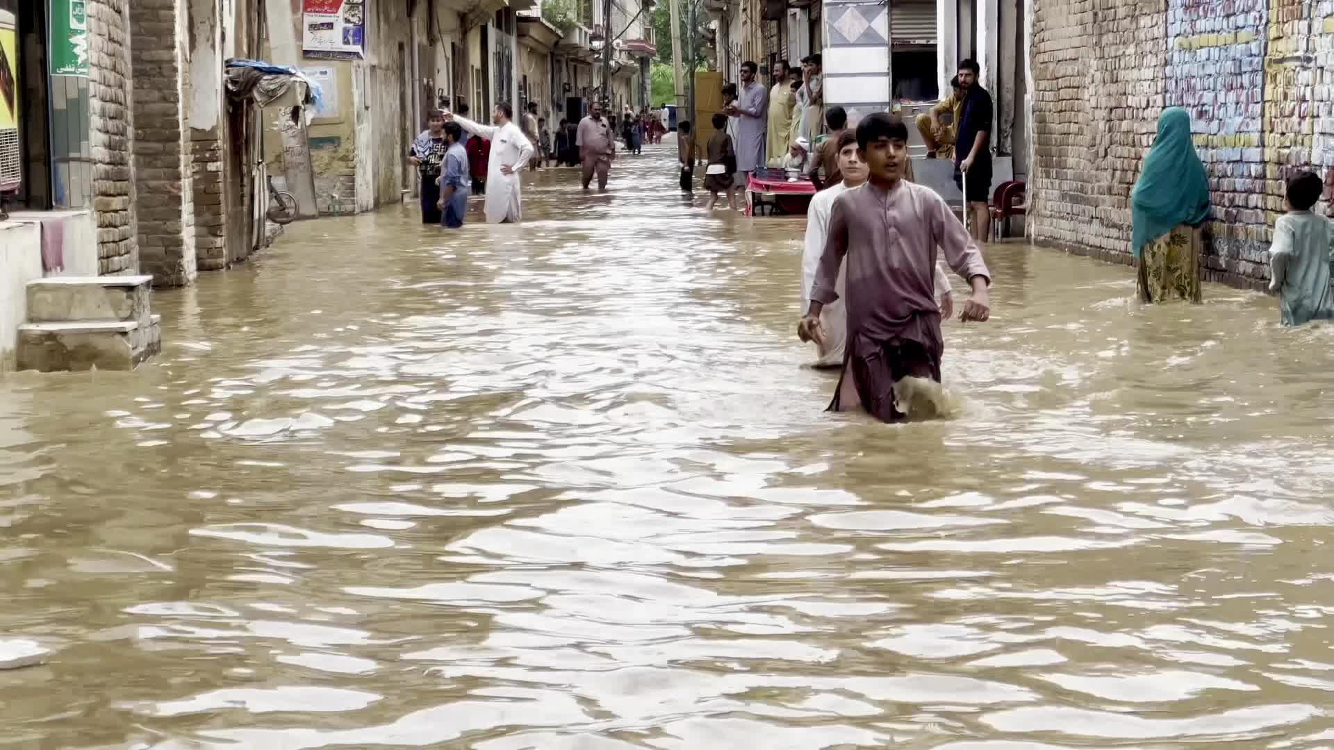 Residents wade through floodwaters after heavy monsoon rains in Peshawar