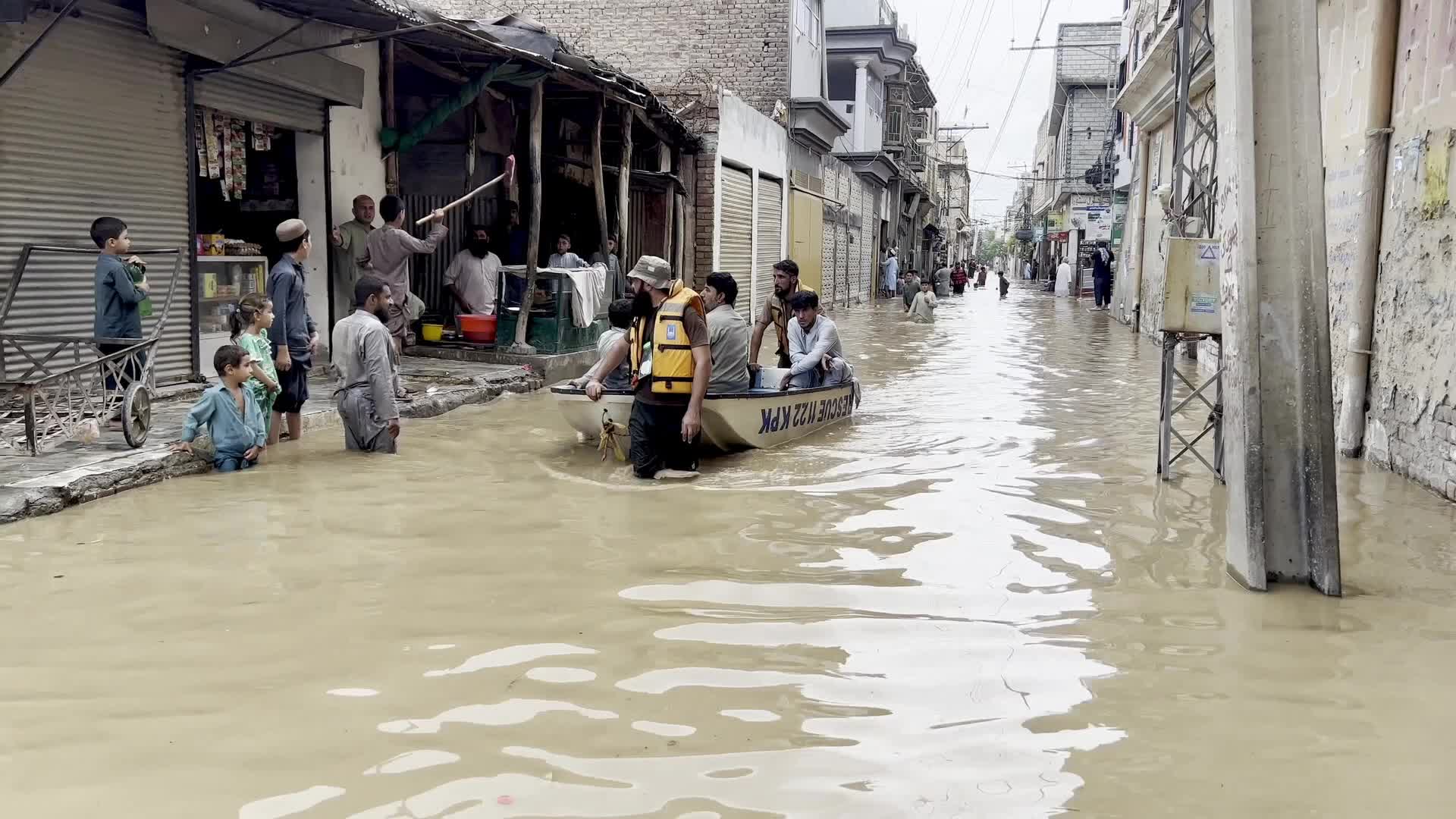 Residents wade through floodwaters after heavy monsoon rains in Peshawar