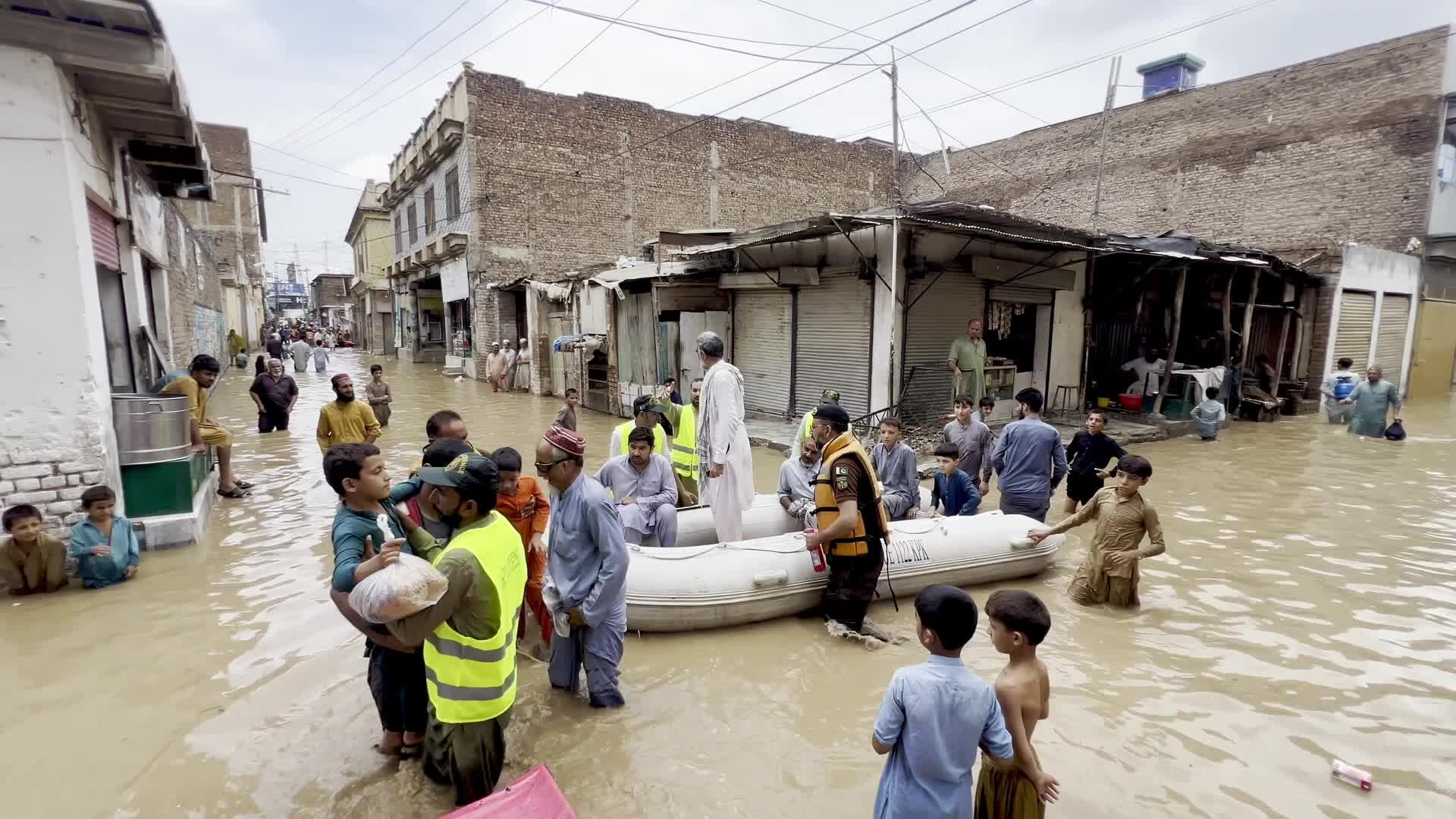 Residents wade through floodwaters after heavy monsoon rains in Peshawar