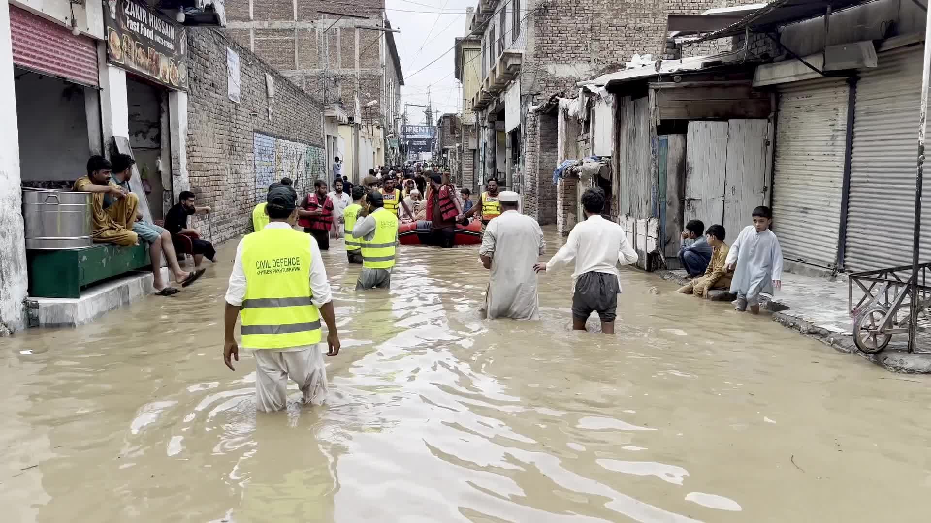 Residents wade through floodwaters after heavy monsoon rains in Peshawar