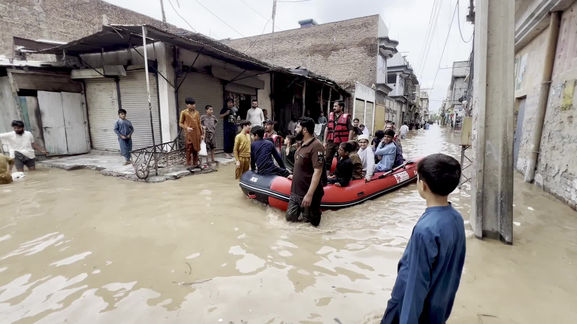 Residents wade through floodwaters after heavy monsoon rains in Peshawar