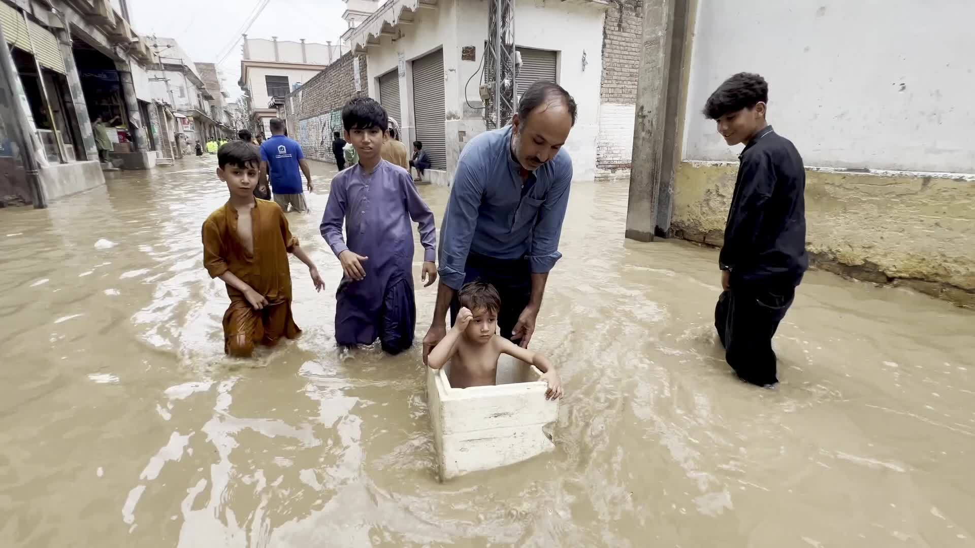 Residents wade through floodwaters after heavy monsoon rains in Peshawar
