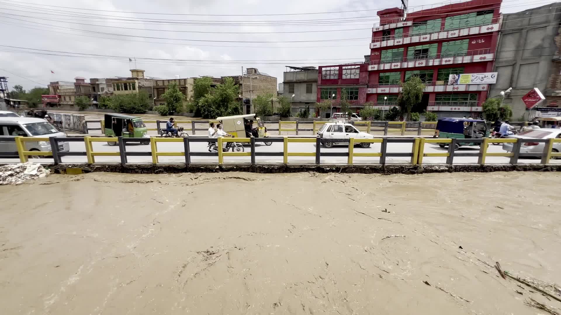Residents wade through floodwaters after heavy monsoon rains in Peshawar