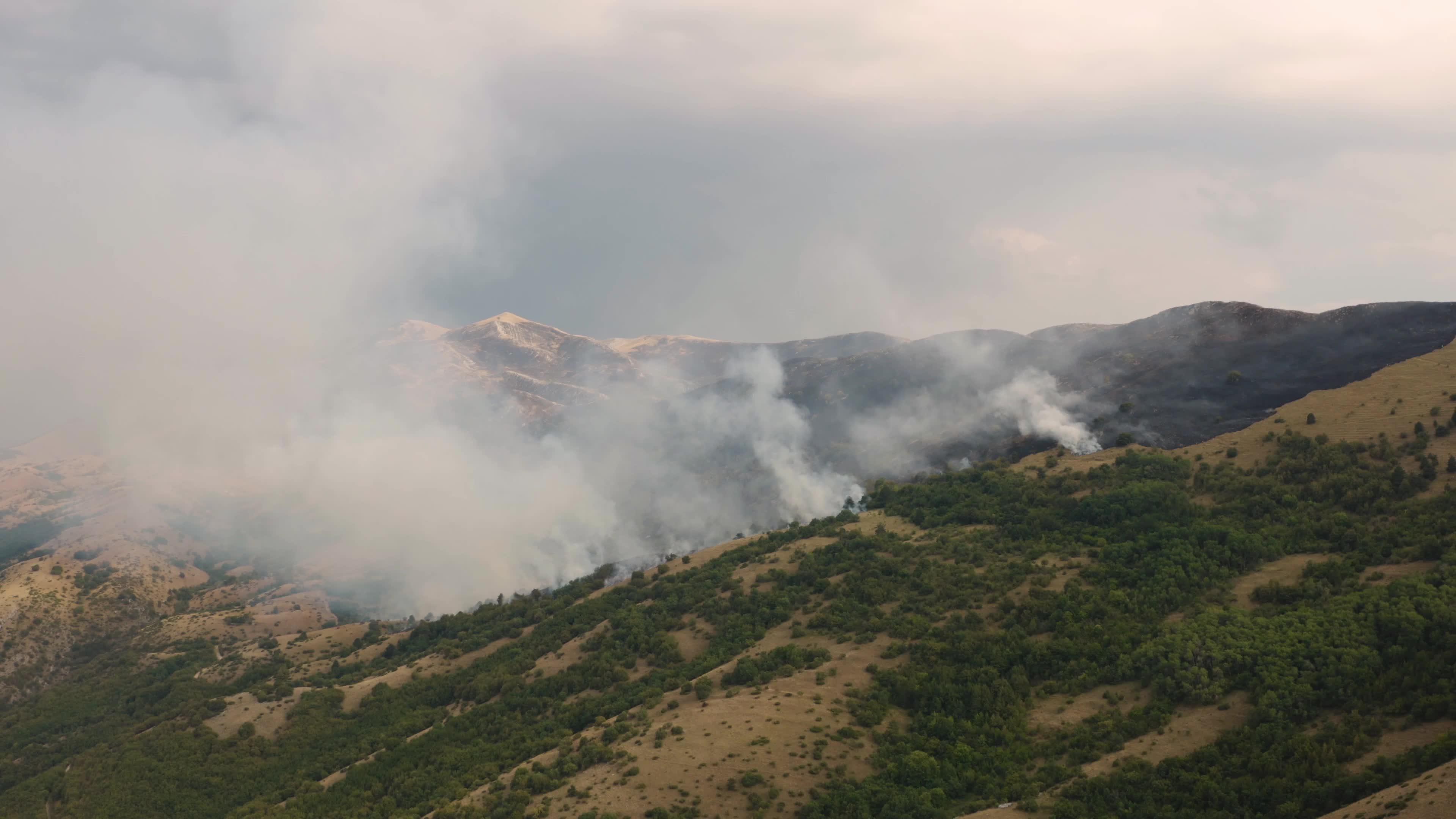 Aerial drone view of mountain wildfire and smoke plume in Italy climate change emergency