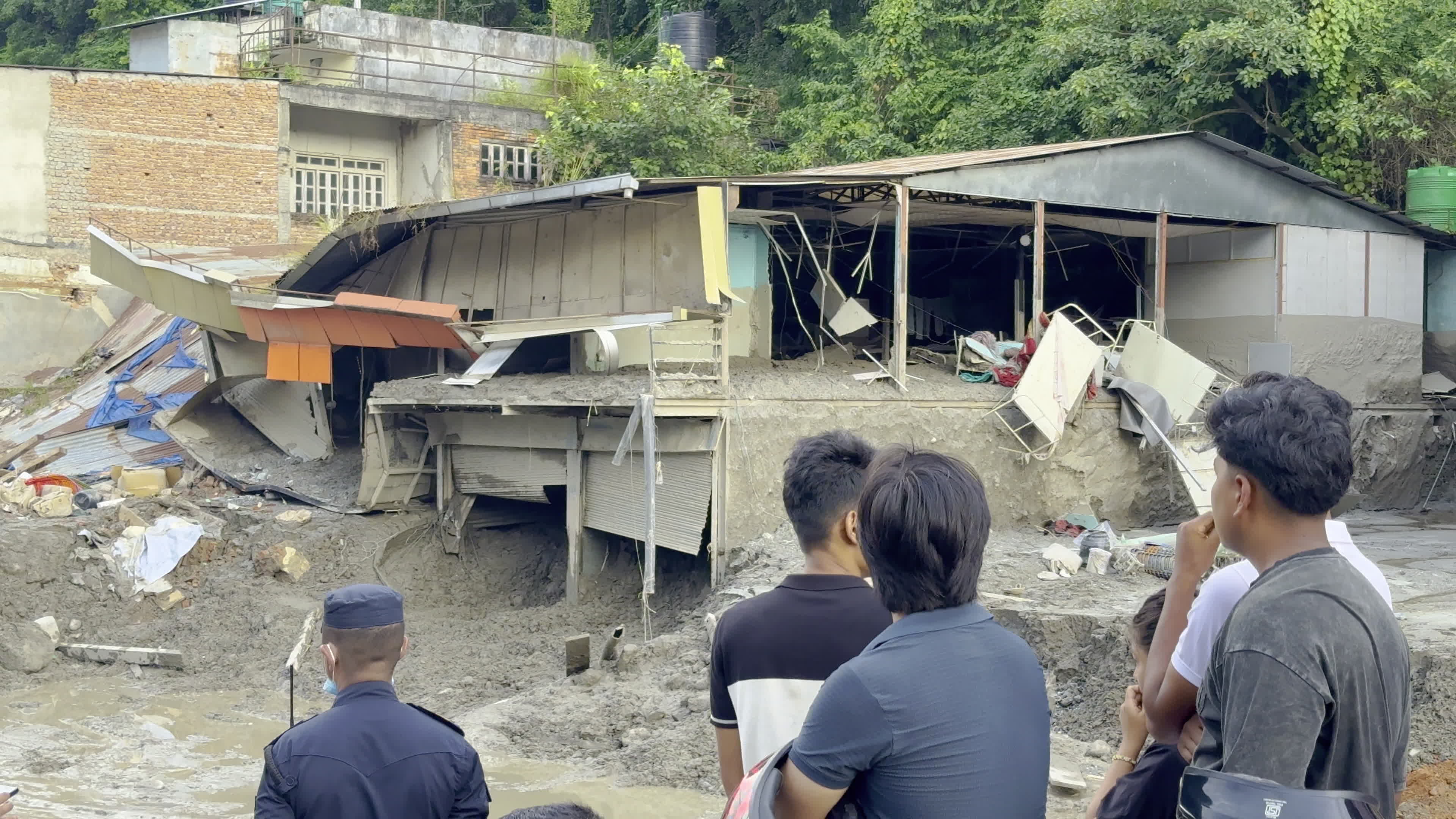 NEPAL: Onlookers and Police Inspect Collapsed Commercial Structure Following Trishuli Flood