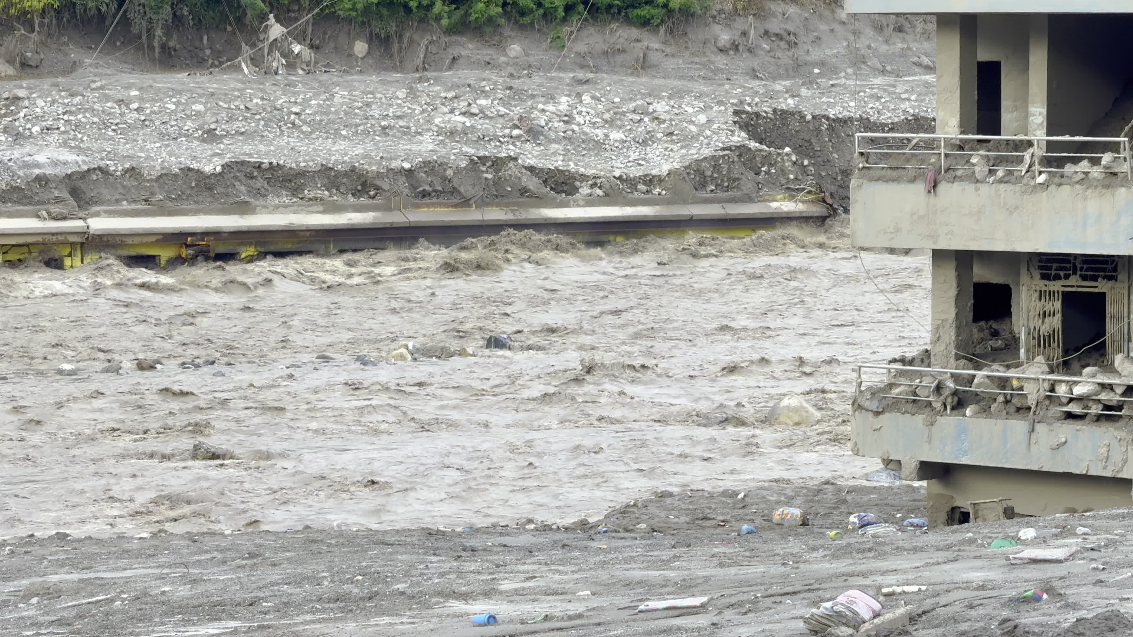 NEPAL: Swollen Trishuli River Rapids Inundate Riverside Building and Bridge Structure