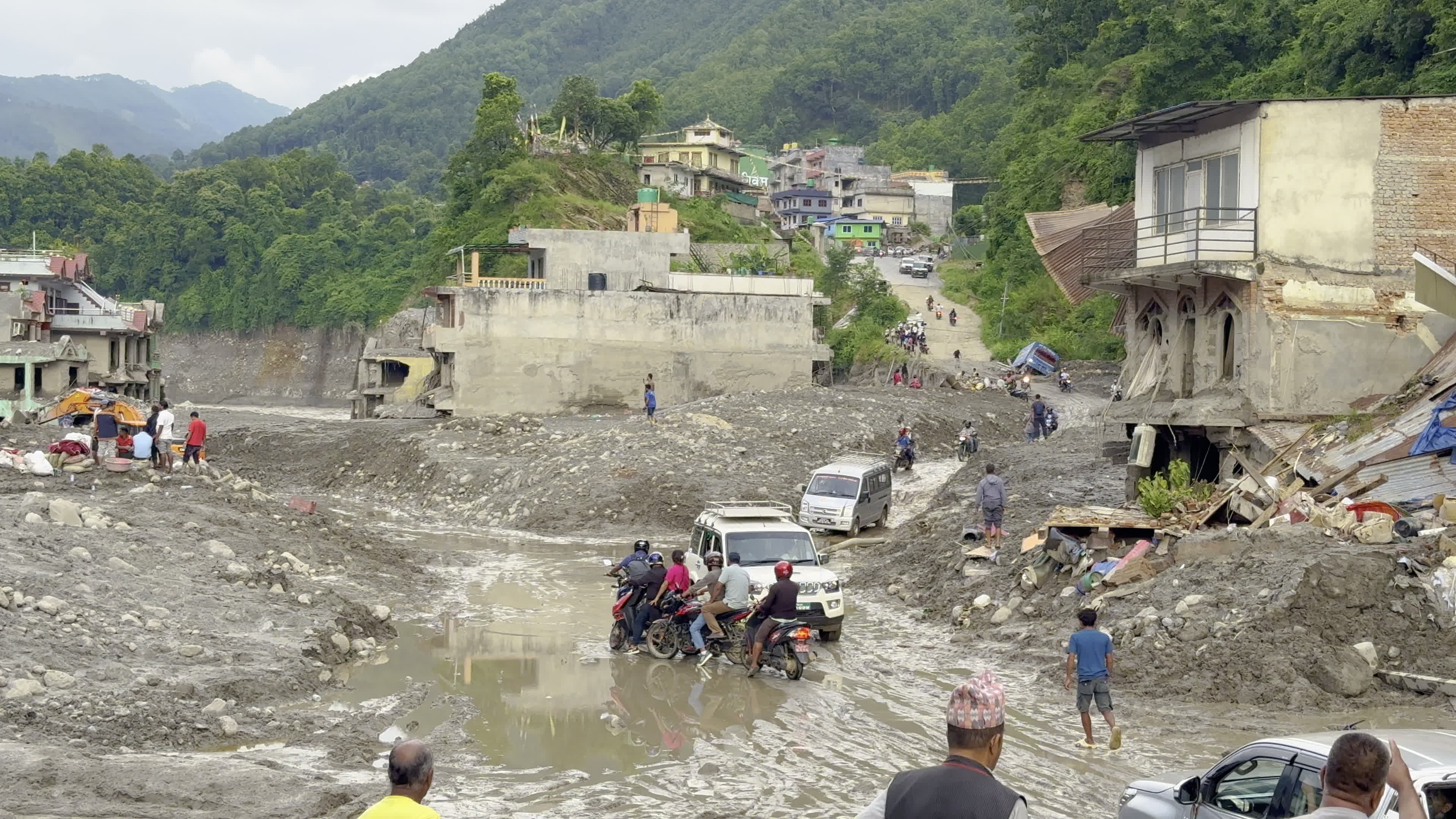 NEPAL: Vehicles and Motorcyclists Wade Through Mud-Choked Trishuli Highway After Trishuli River Flood