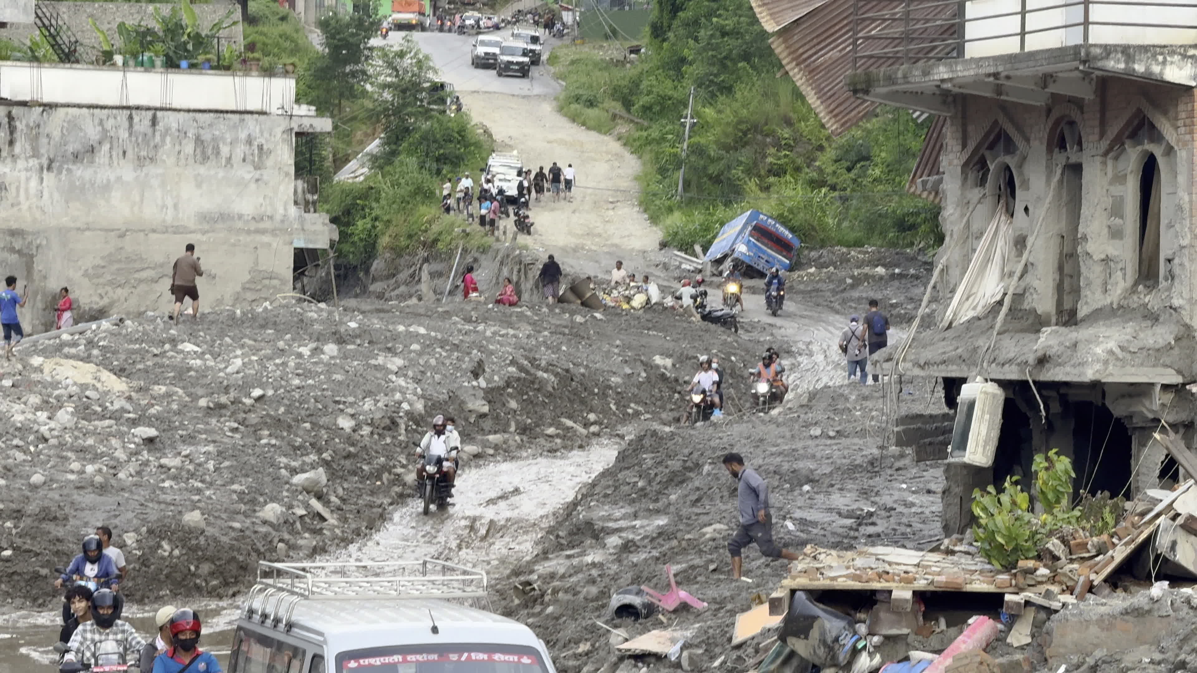 NEPAL: Motorcyclists and Commuters Navigate Silt-Filled Road and Stranded Truck After Trishuli Flood