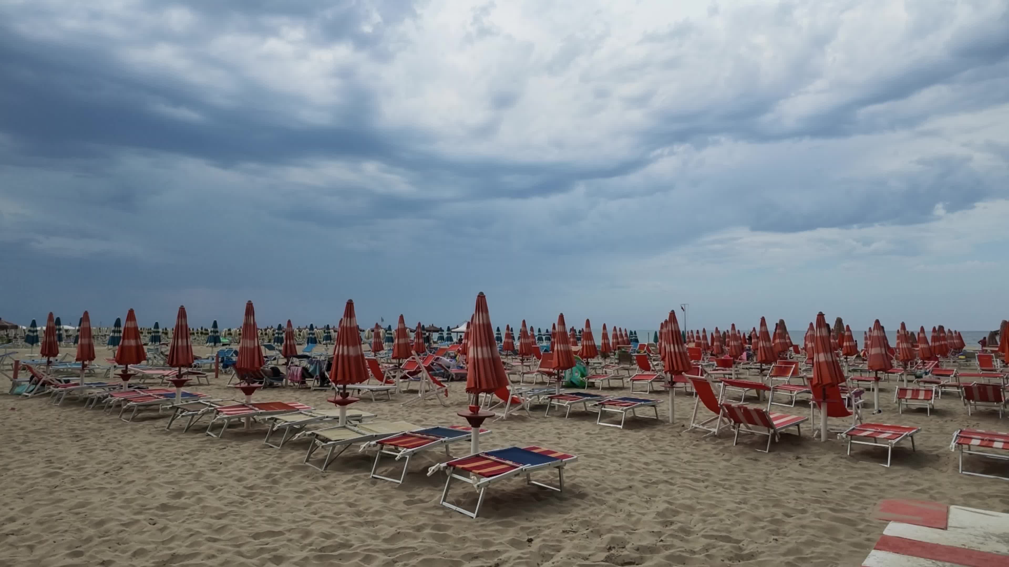 End of summer season on a quiet Italian beach with closed umbrellas and few people