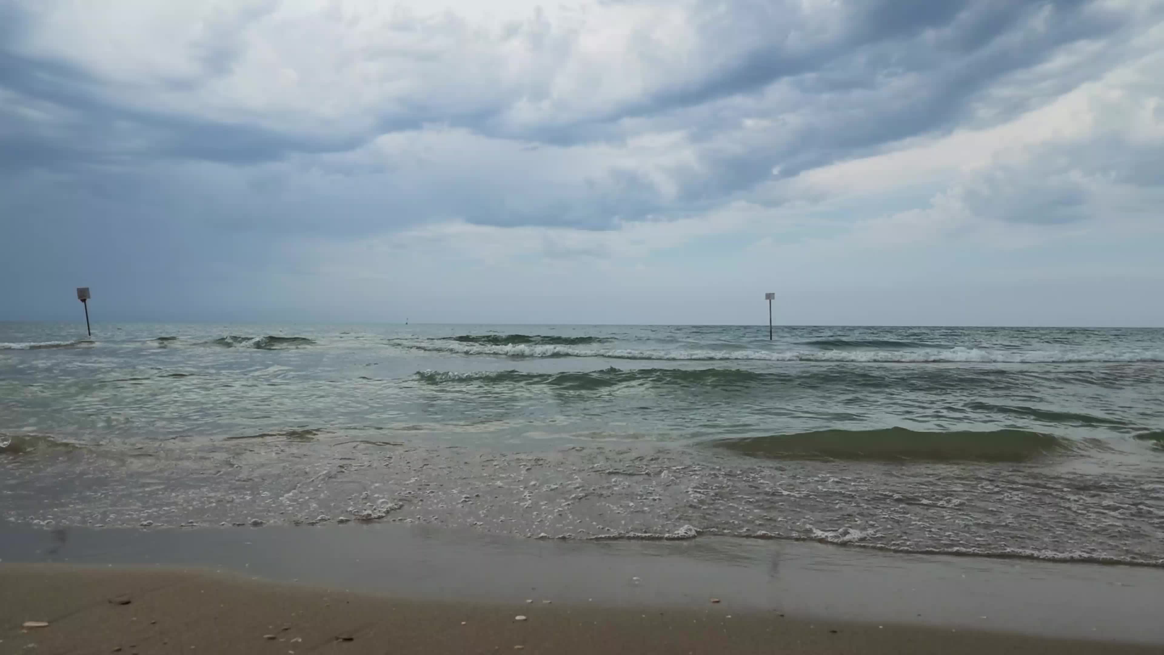 End of summer season on a quiet Italian beach with closed umbrellas and few people
