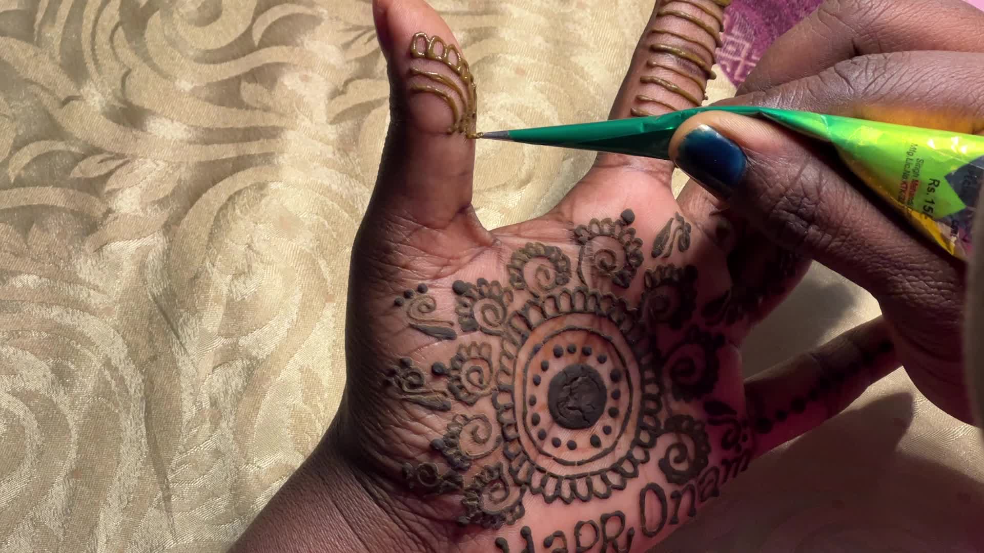 Mehndi is applied to the hands of a woman during the Onam festival