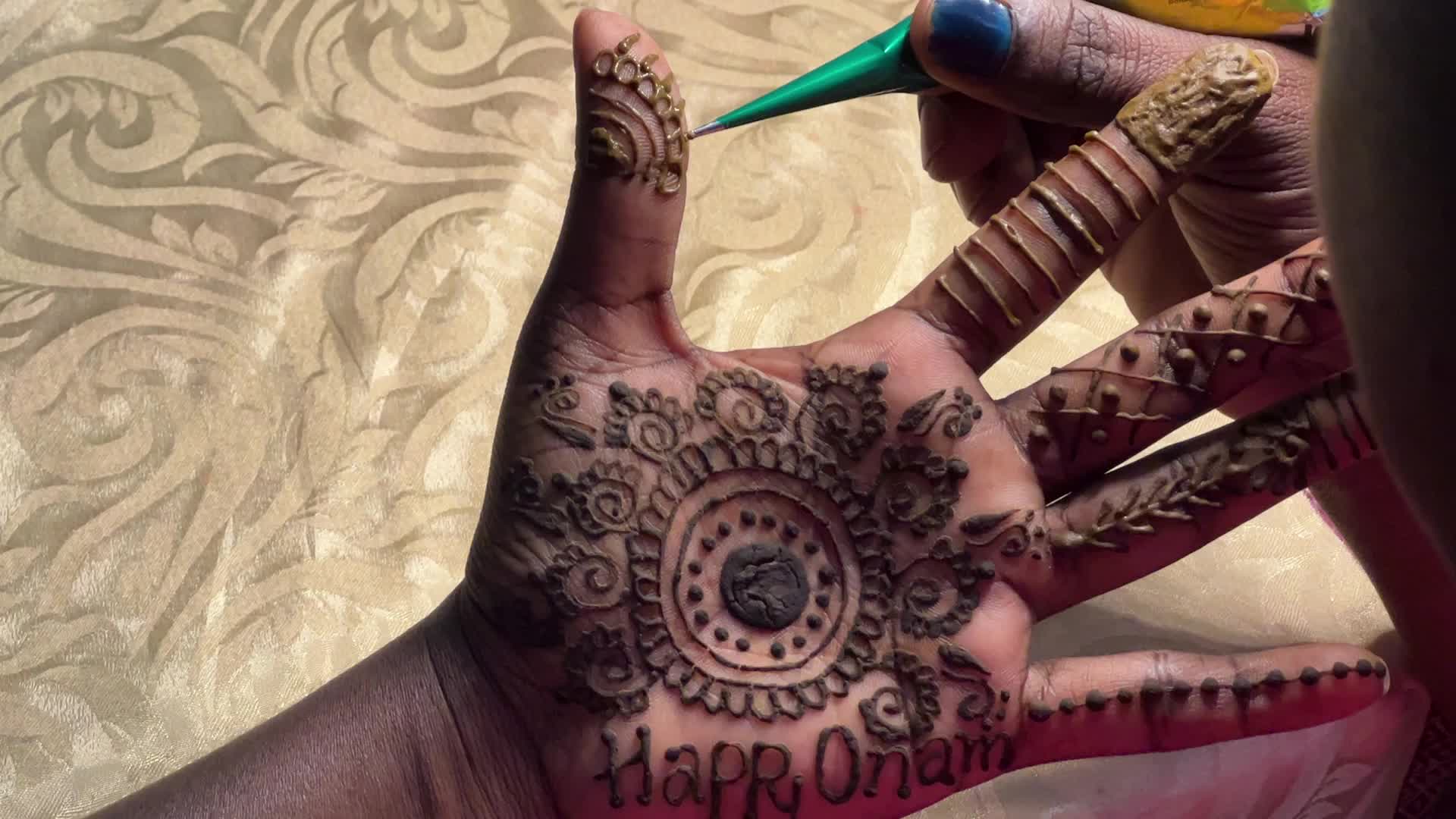 Mehndi is applied to the hands of a woman during the Onam festival