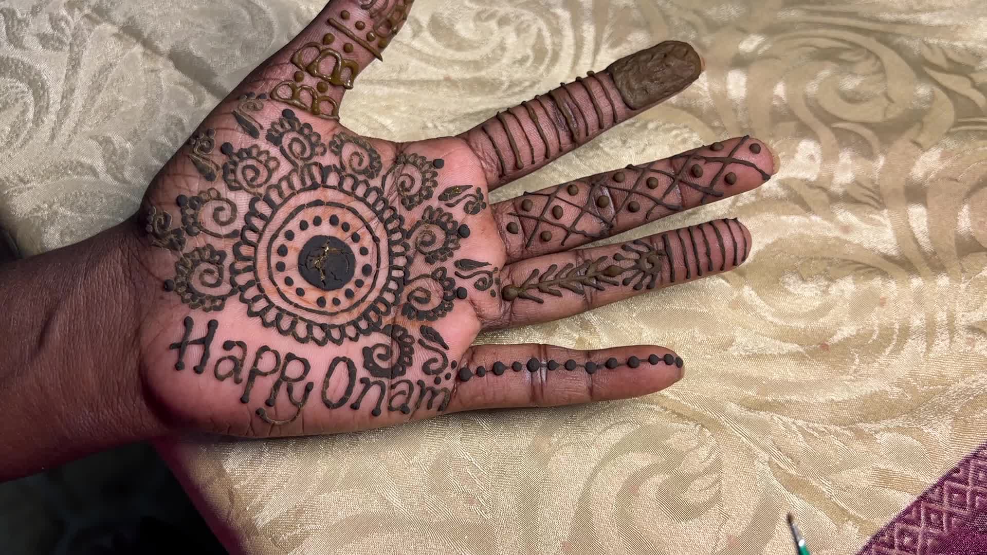 Mehndi is applied to the hands of a woman during the Onam festival