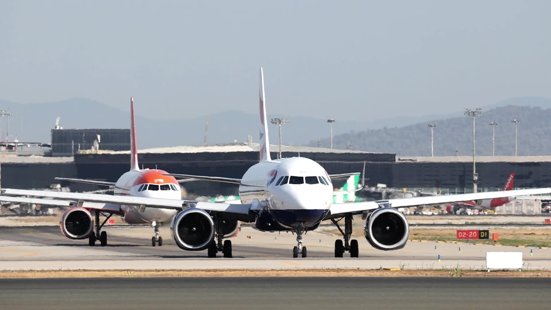 A British Airways and an easyJet Airbus A320 prepare to take off from Barcelona Airport