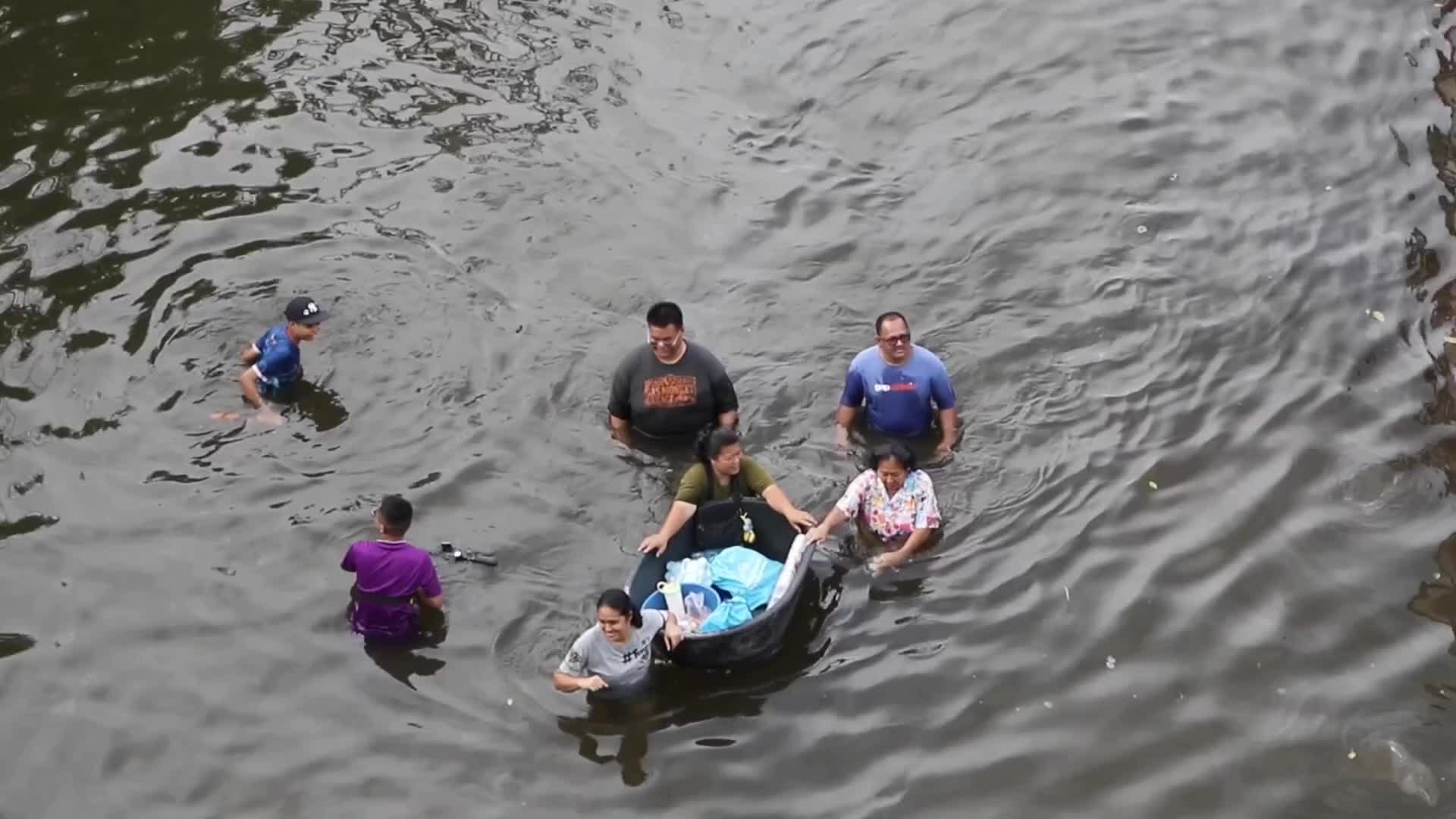 Bangkok residents walk in floodwater.