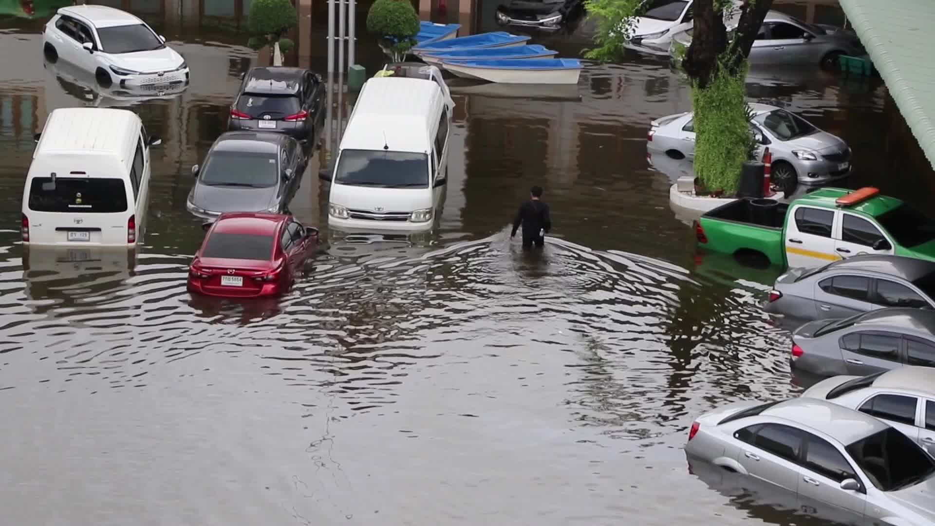 Man walks in past damage vehicles from floods