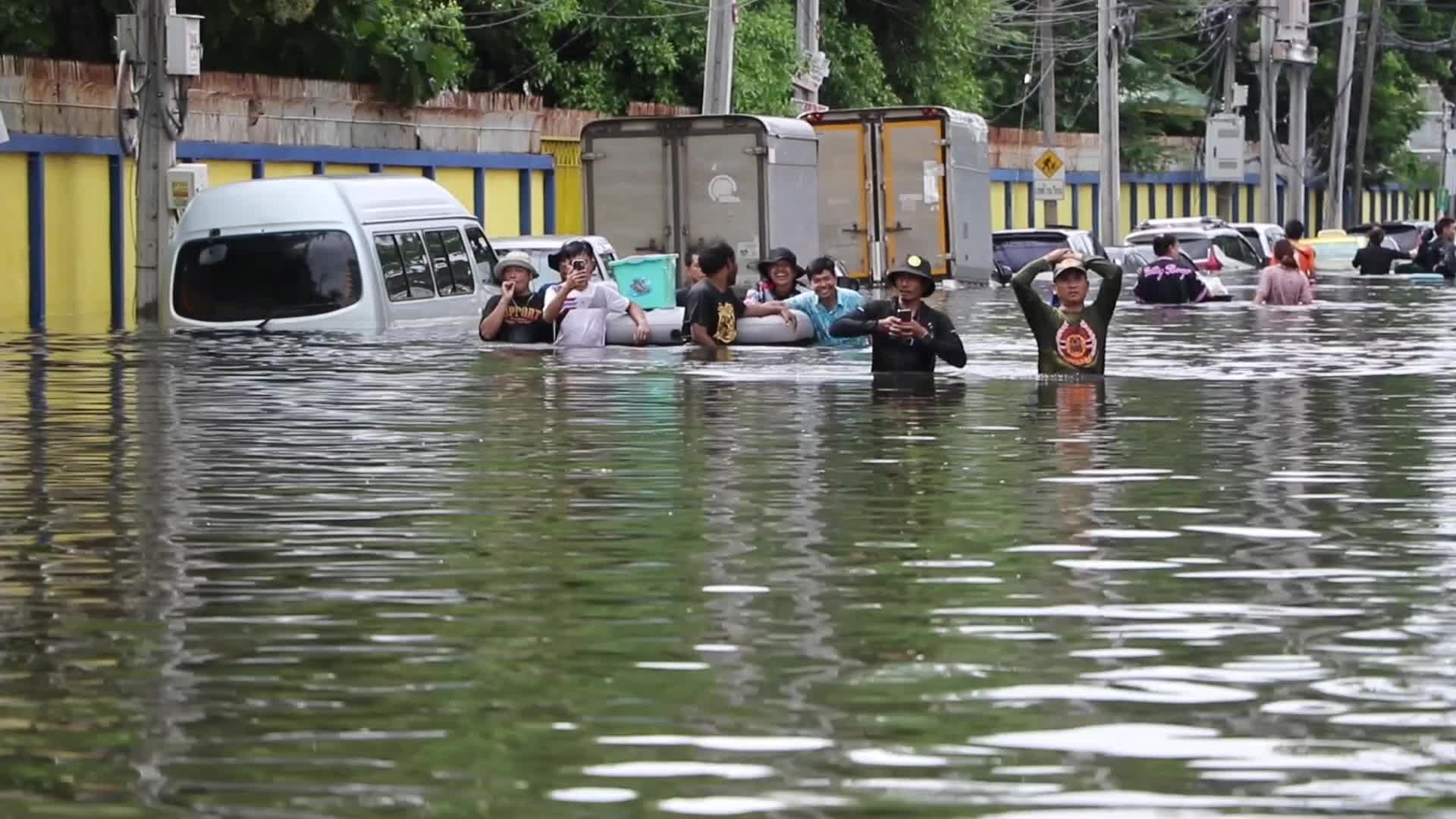 Bangkok residents and rescue workers walk in floodwater.