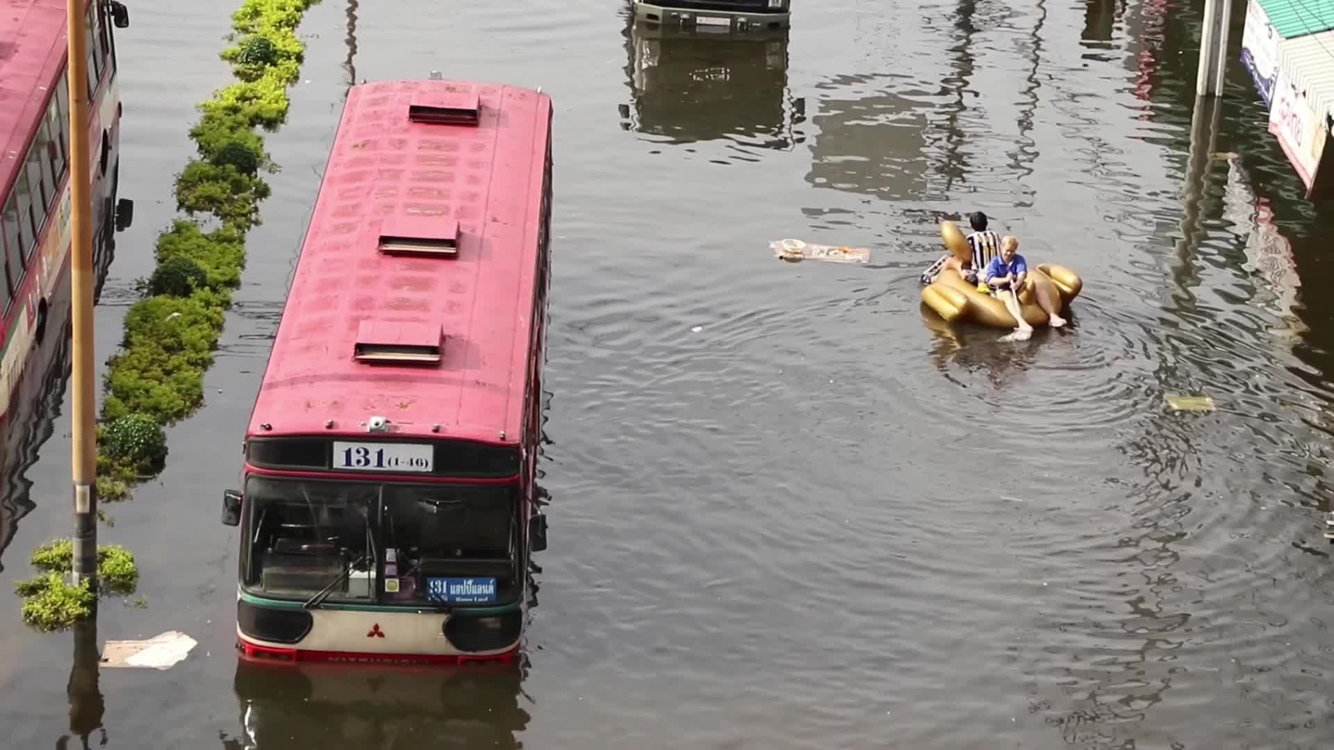 A couple sits on pool float past damage bus.