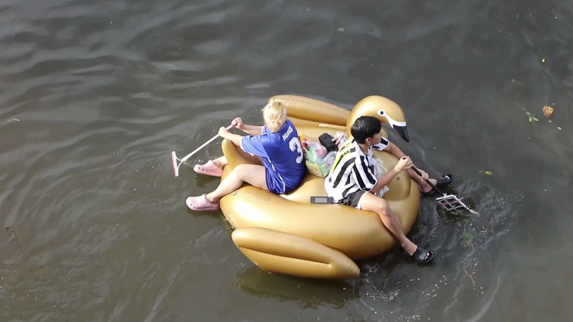 A couple  sits on pool float in floodwater.