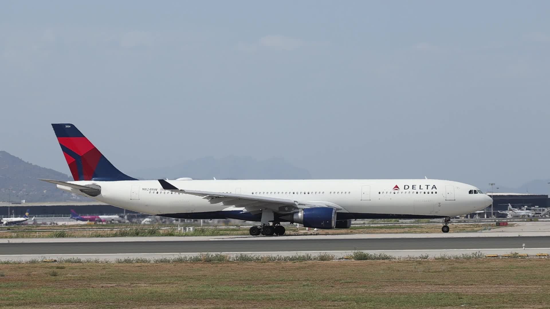 A Delta Air Lines Airbus A330 heads toward the takeoff runway as a Vueling aircraft takes off