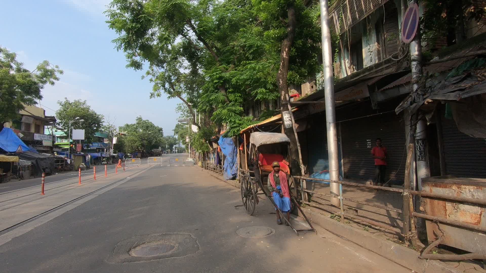 Hand rickshaw puller is sitting on his rickshaw on a deserted road in Kolkata