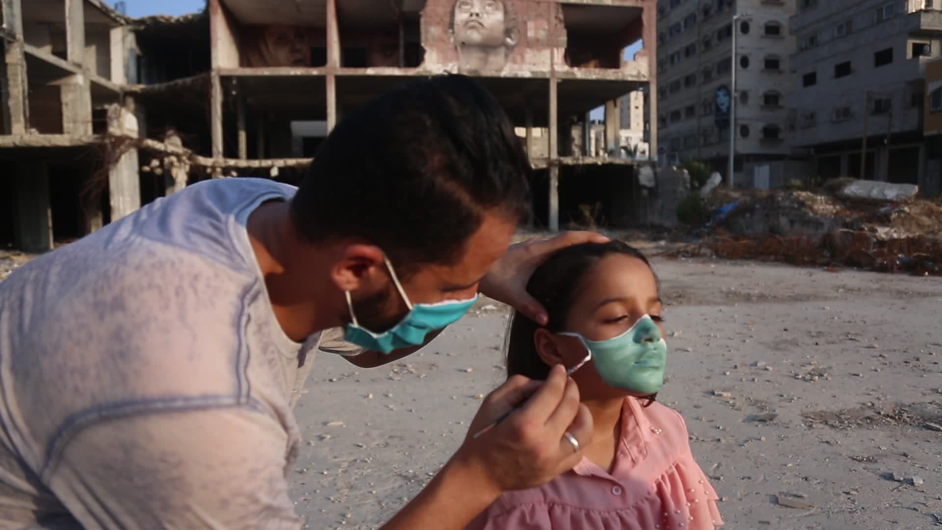 Palestinian artist draws a mask to childs in Gaza