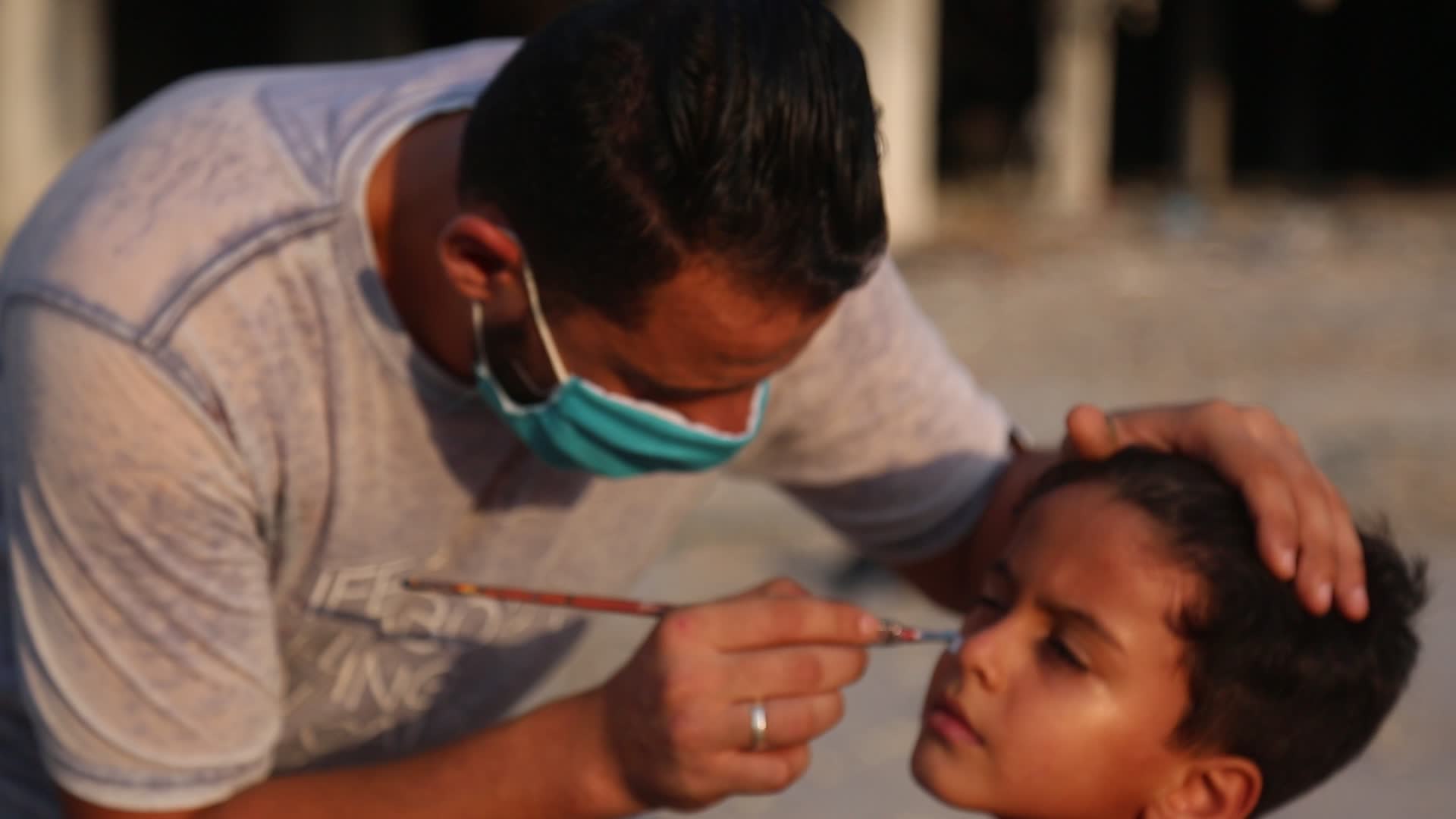 Palestinian artist draws a mask to childs in Gaza