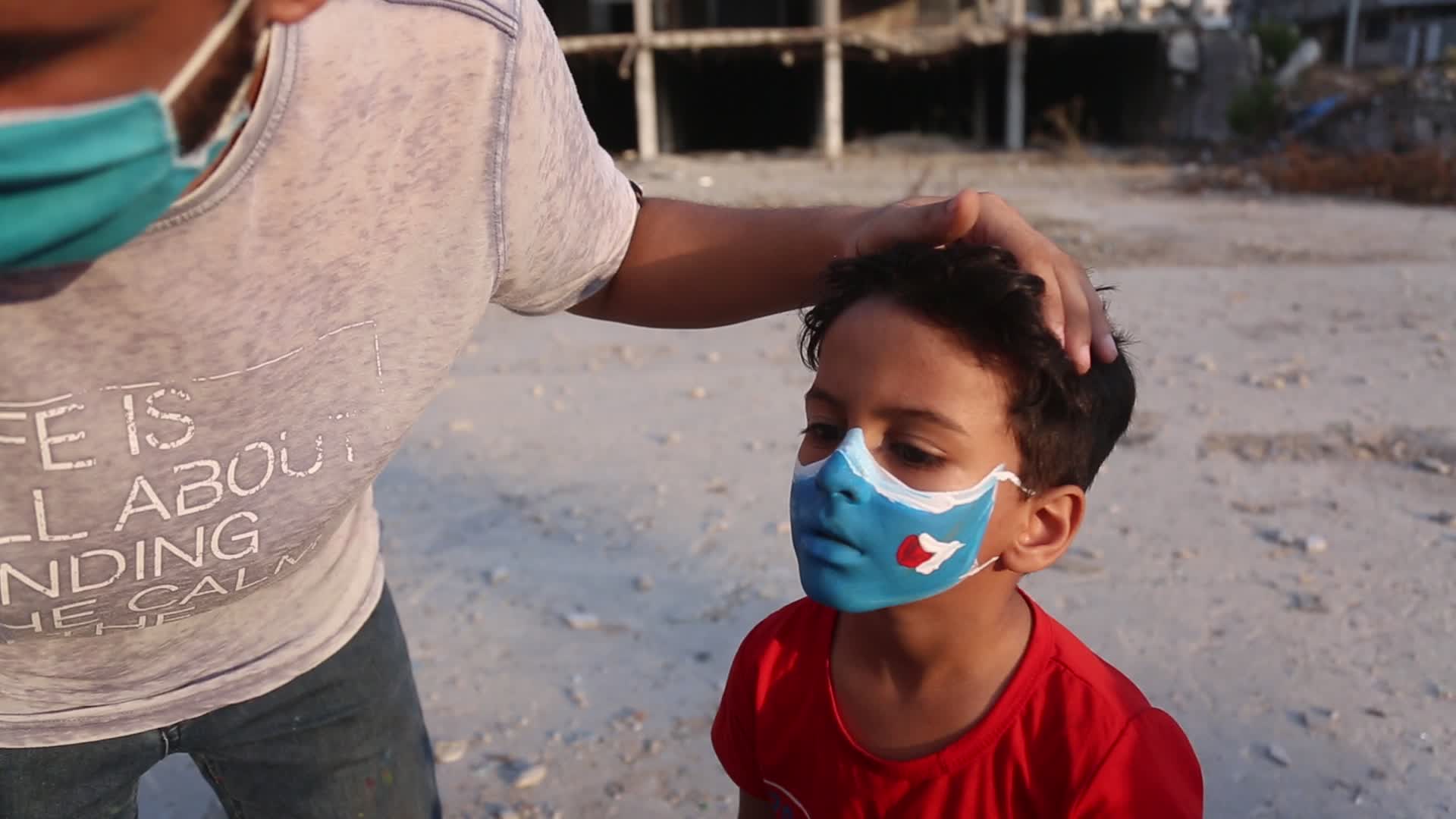 Palestinian artist draws a mask to childs in Gaza