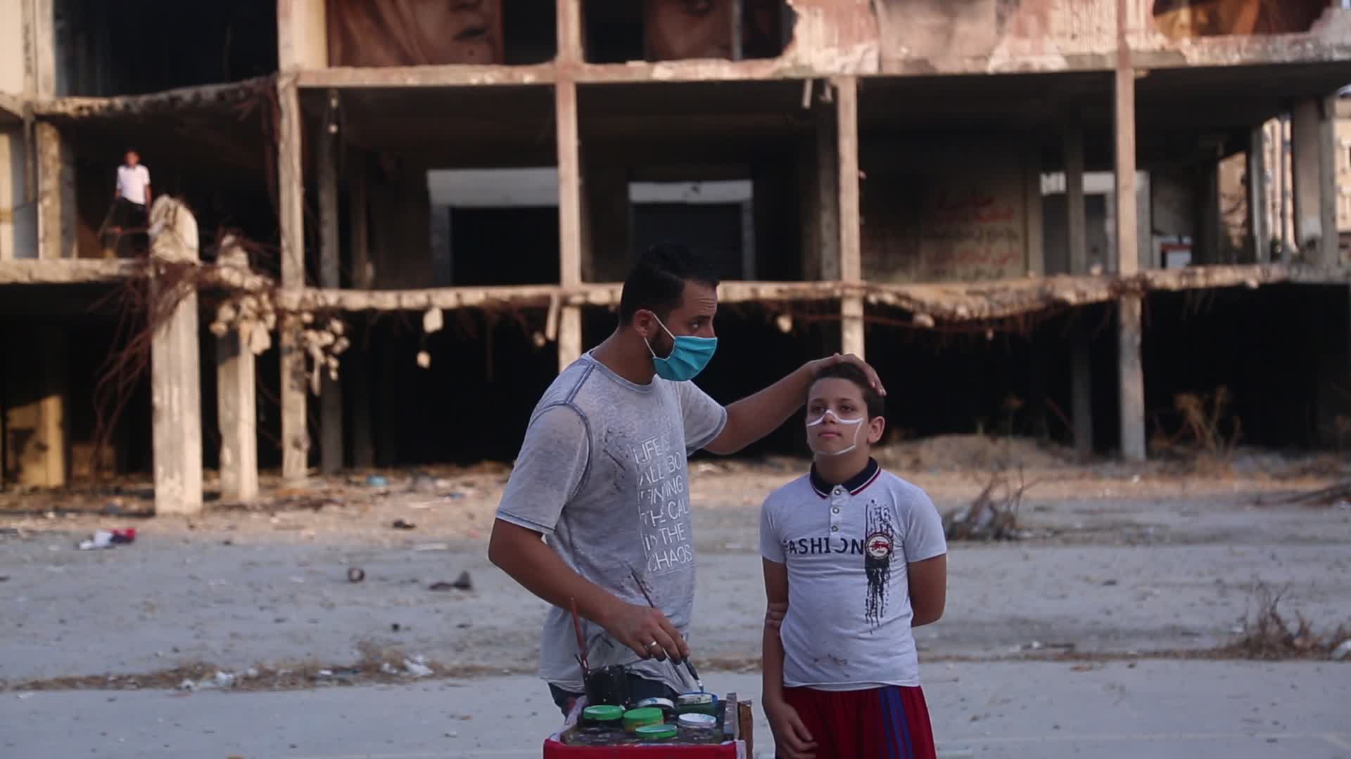 Palestinian artist draws a mask to childs in Gaza