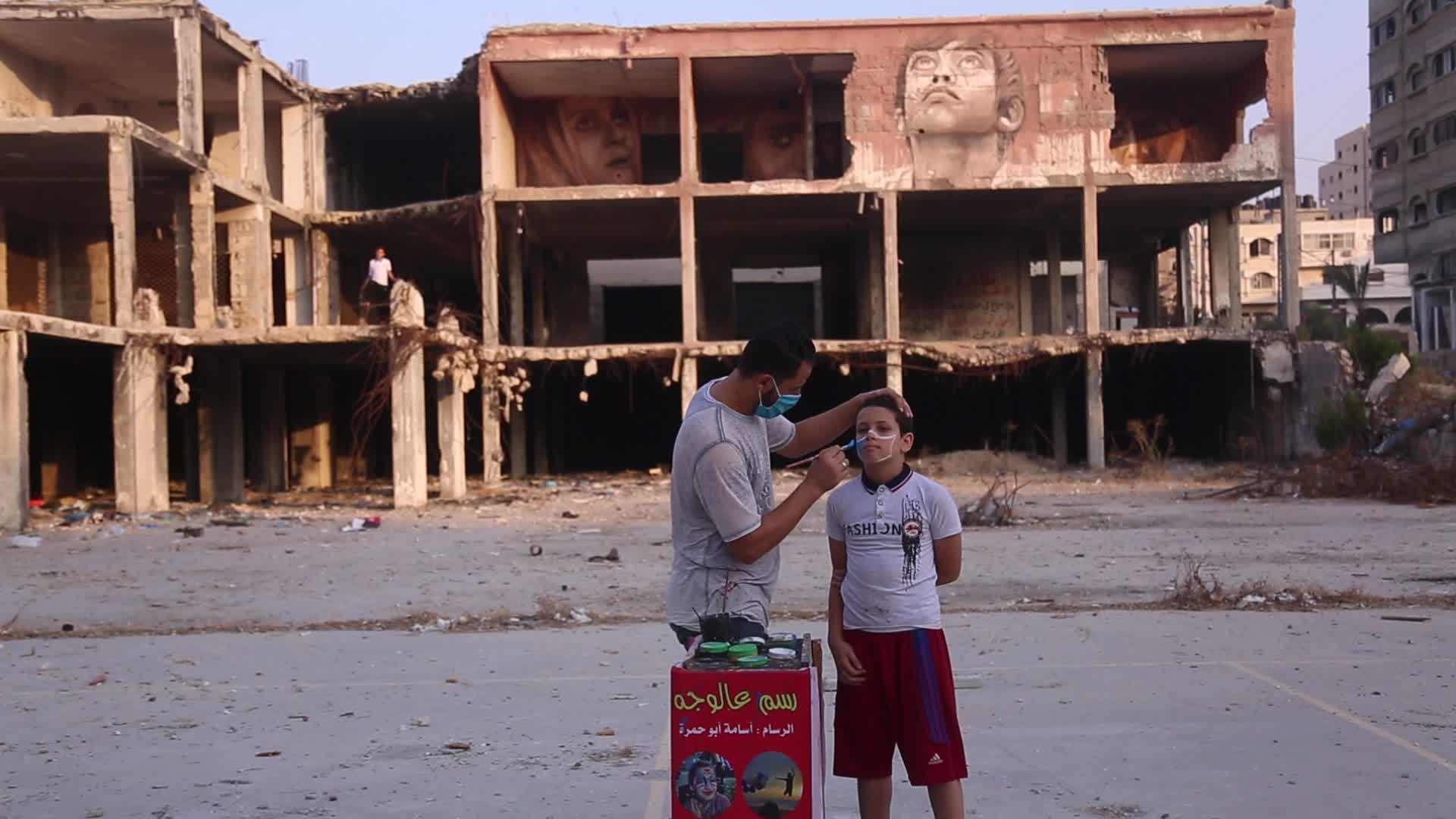 Palestinian artist draws a mask to childs in Gaza