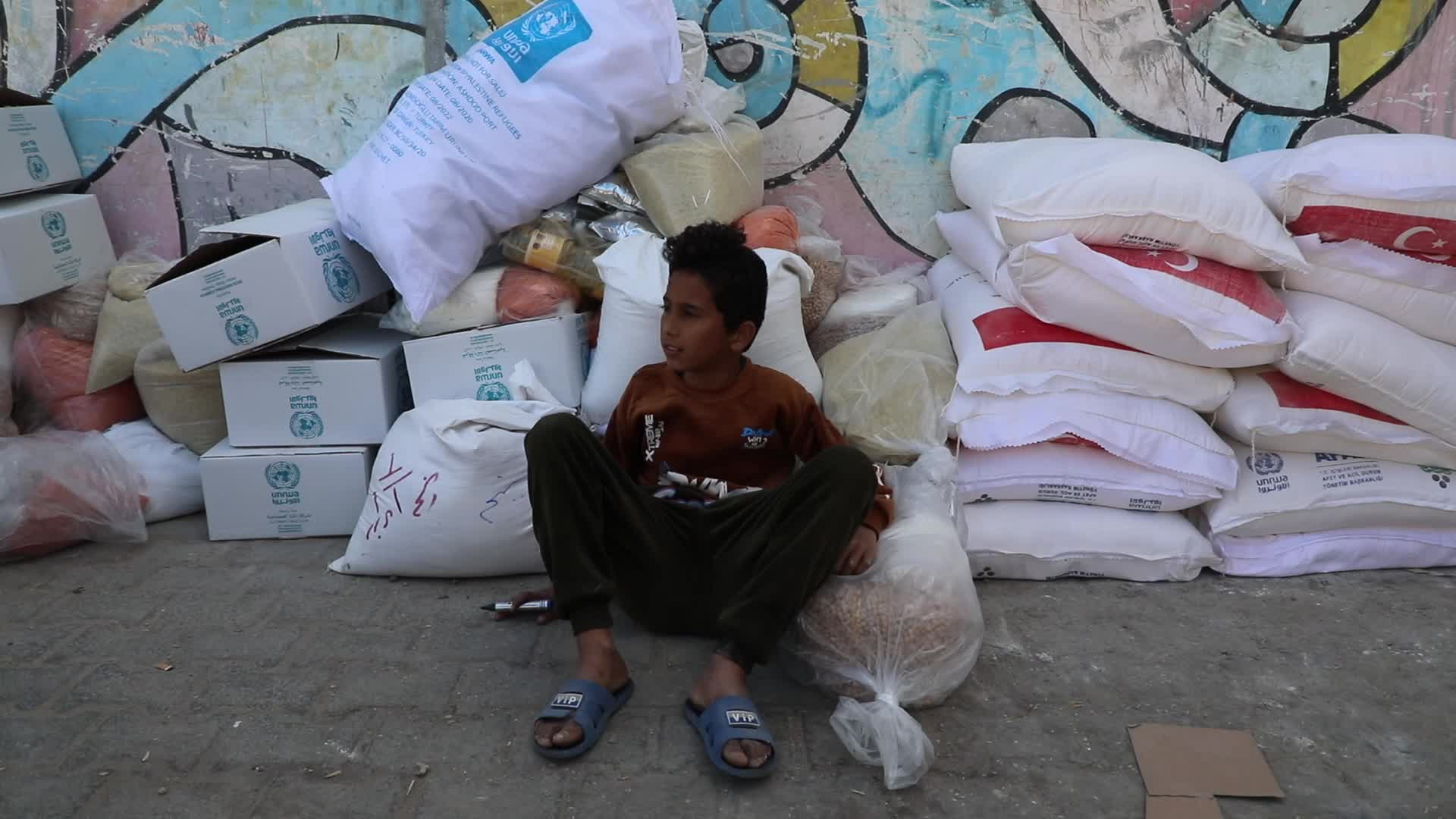 Palestinian refugees receive aid distributed by UNRWA in Gaza