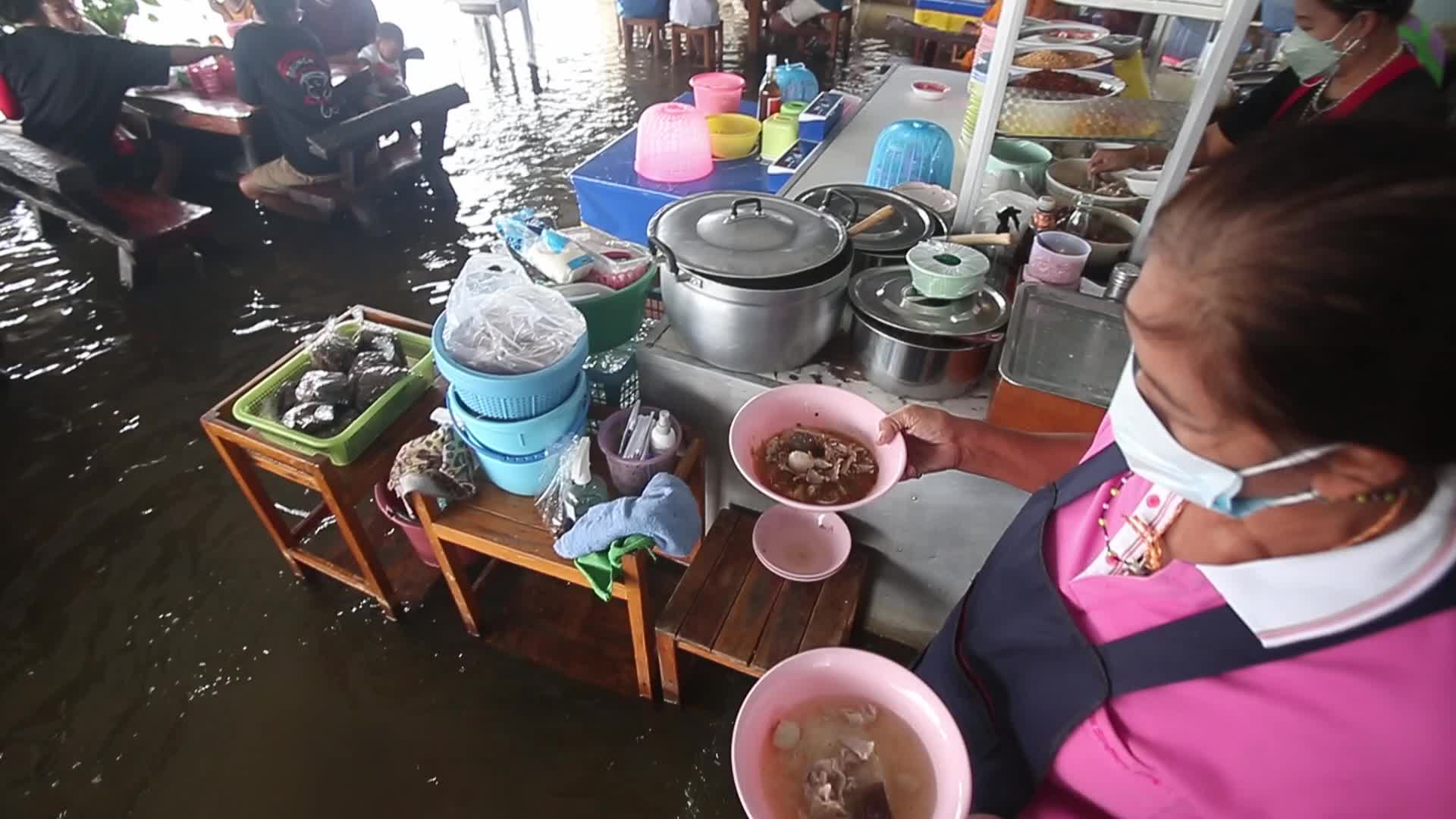 Water overflows from the Tha Chin river in a flooded-noodle shop